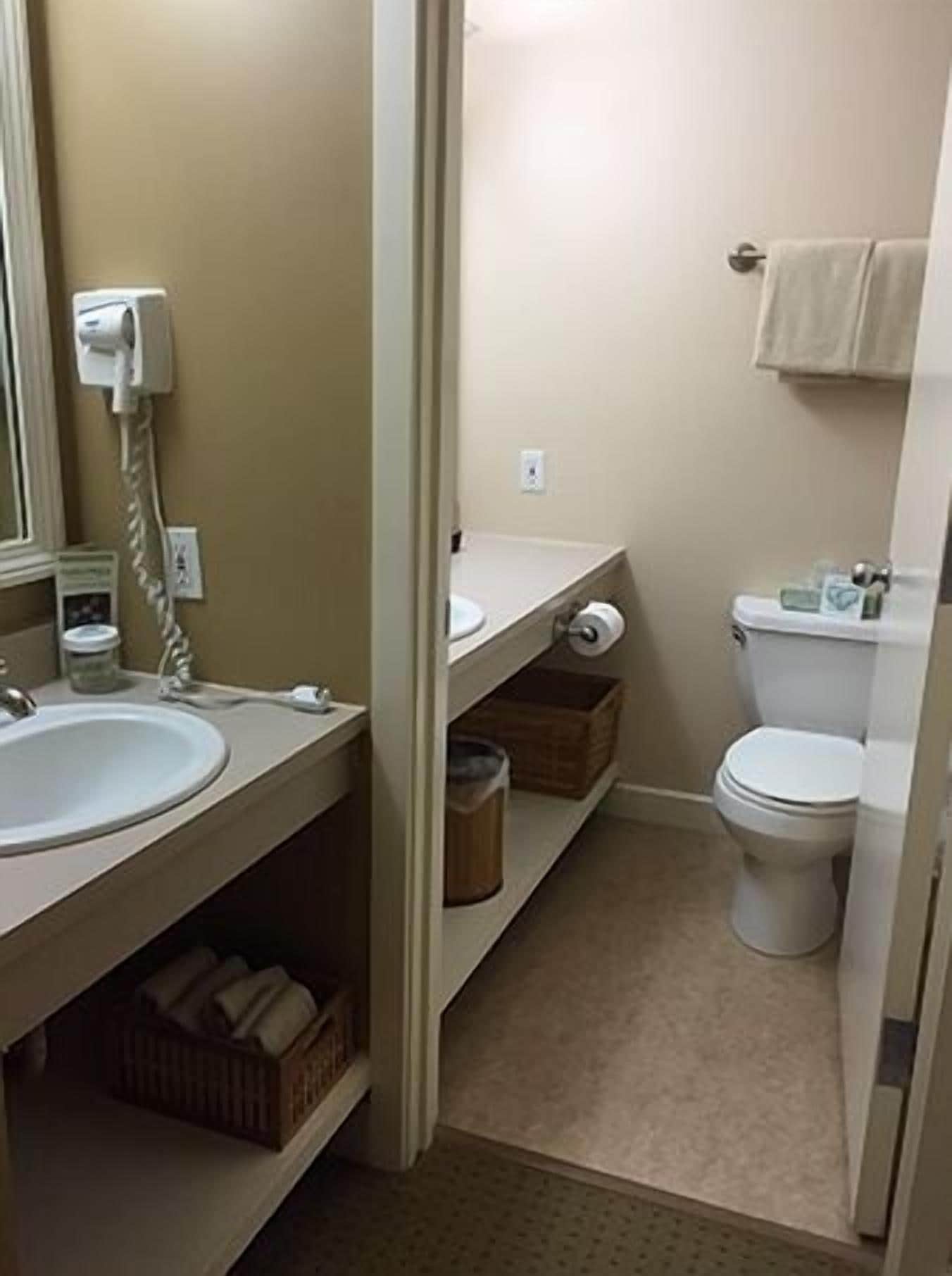 Et lille badeværelse med vask, toilet og håndklæderække.