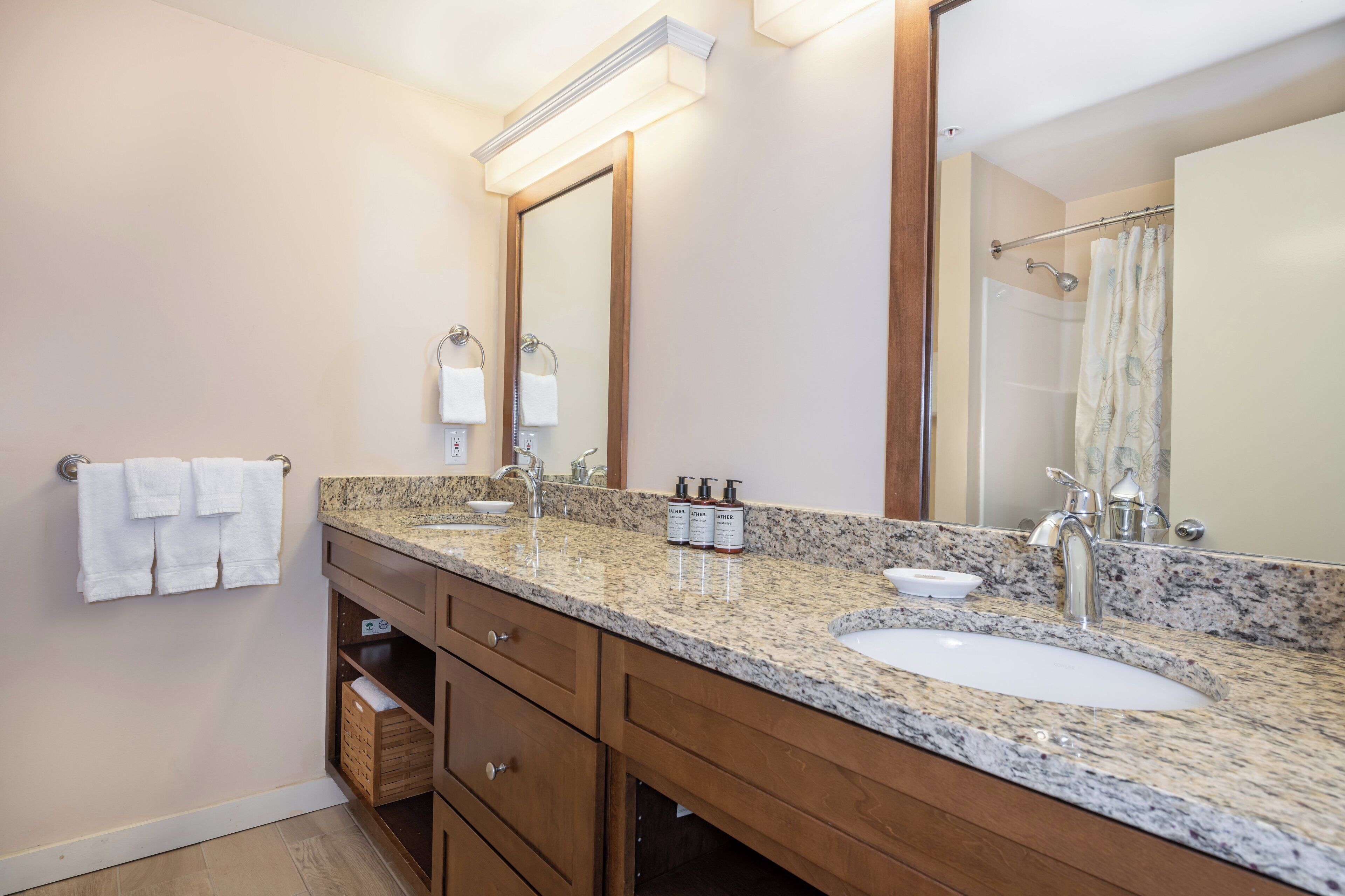 Une salle de bain avec deux lavabos, un grand miroir et des meubles en bois.