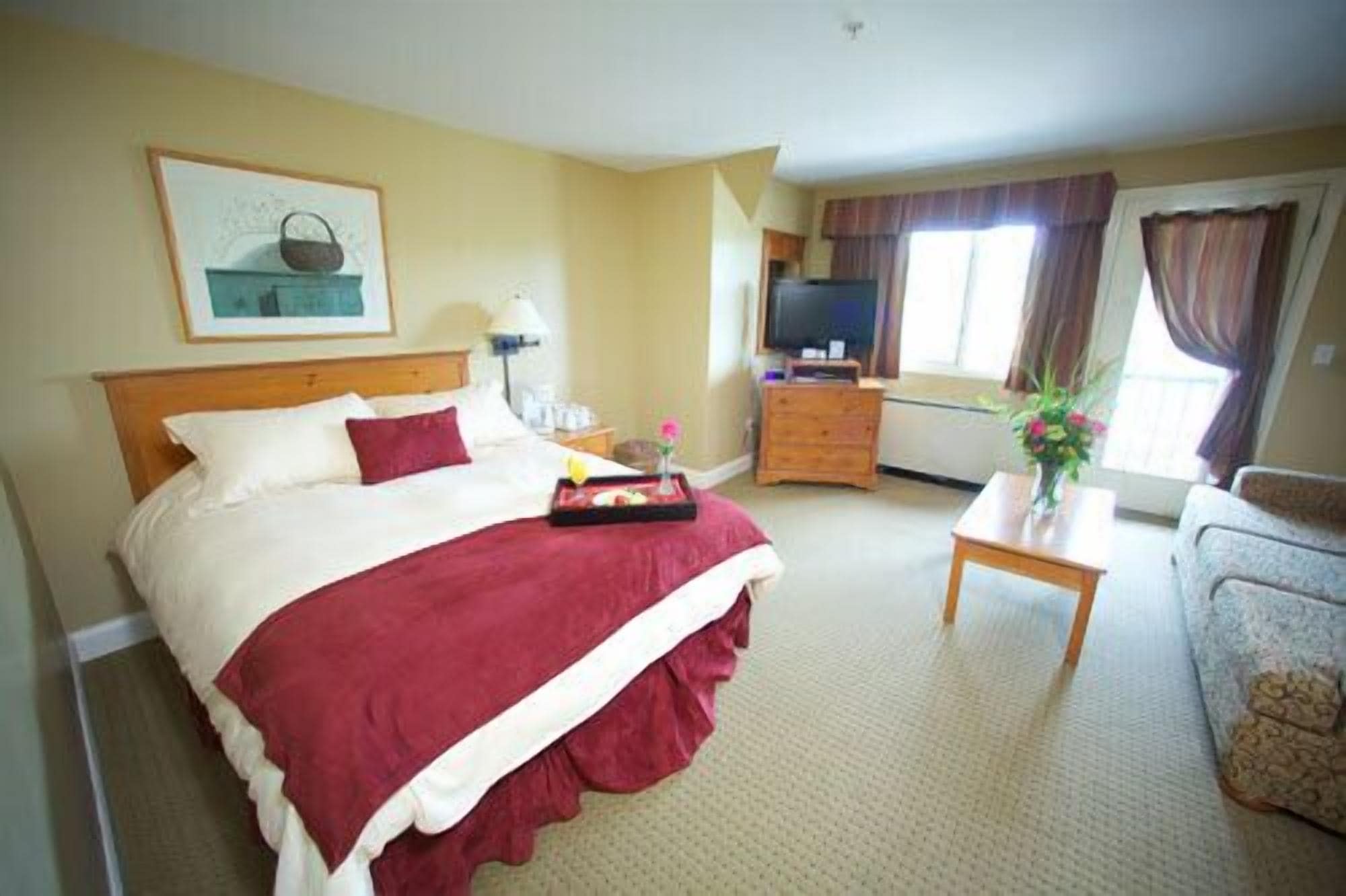 A hotel room with a bed, a desk, a television, and a window with curtains.