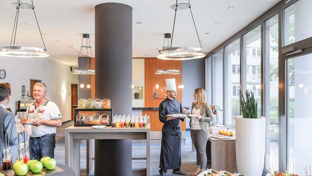 Una barra de buffet con diversos alimentos y un chef atendiendo a los comensales.
