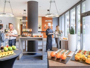 A buffet setup with various food items and a chef serving guests. - Novotel Erlangen (Erlangen)