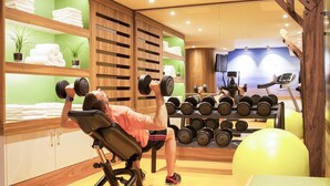 Un gimnasio con equipo de ejercicio, una cinta de correr y un espejo.