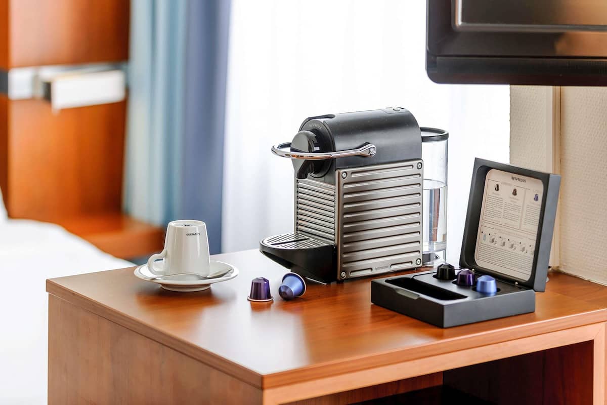 A coffee machine with a manual, a cup, and a saucer on a wooden table.