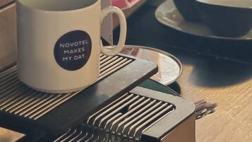 Une machine à café avec une tasse de café posée sur un plateau, un tableau affichant le menu et un pot de sucre.