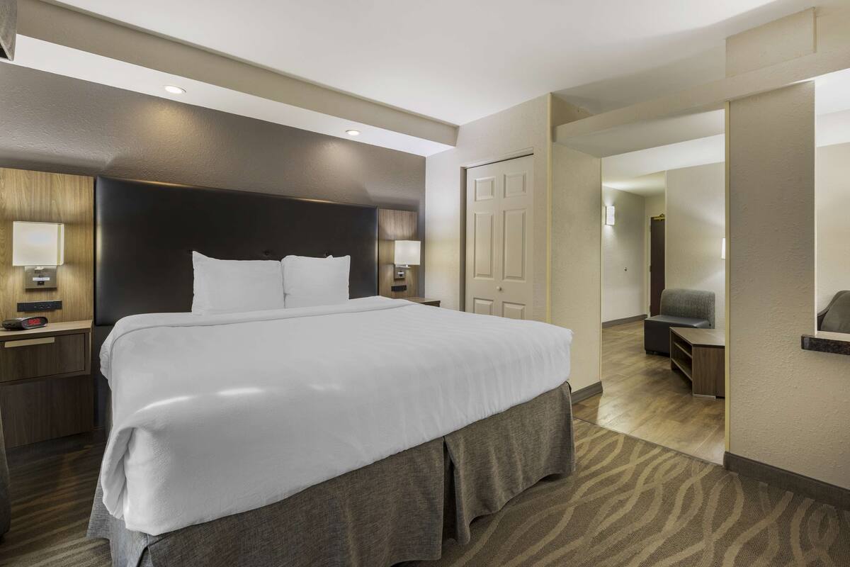 A modern hotel room with a large bed, bedside tables, a desk, and a chair.