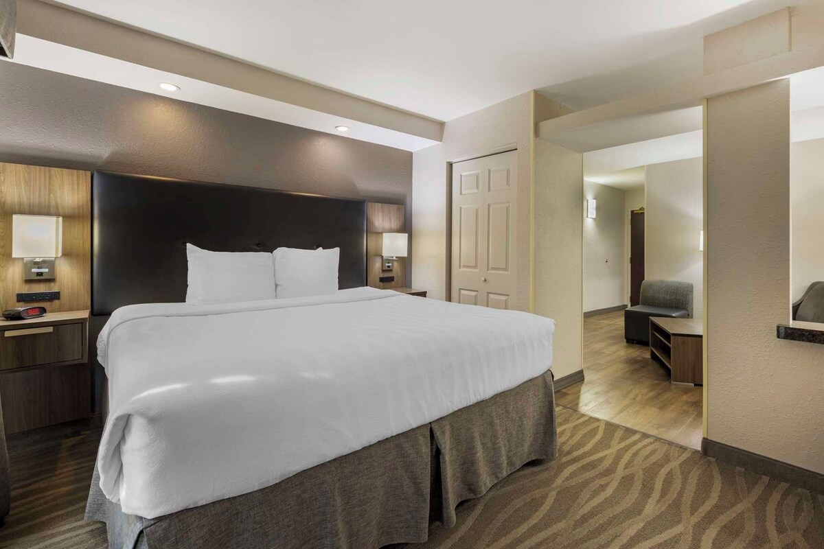 A hotel room with a large bed, bedside tables, a desk, and a chair.
