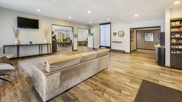 Un vestíbulo moderno con sofá, televisor, mostrador de recepción y zona de estar.