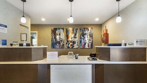 Una recepción con diseño moderno, que destaca una obra de arte grande encima, una pantalla digital y un cartel que indica recompensas de fidelidad.
