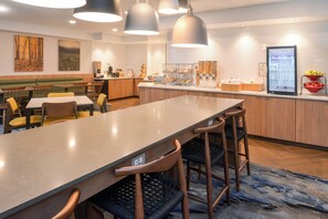 A modern restaurant with a long counter, multiple seating options, and a self-service beverage station. - Fairfield Inn by Marriott Pittsburgh New Stanton (New Stanton)