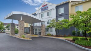 Ein Marriott Inn & Suites Gebäude mit überdachtem Eingang, Steinpfeilern und einem begrünten Bereich mit Bäumen.