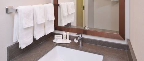 A bathroom with a white sink, a mirror, and two towels hanging on a towel rack.