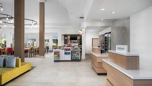 A modern hotel lobby with a reception desk, seating area, and a bar. - Hilton Garden Inn Rockaway (Rockaway)