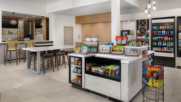 A modern cafe with a bar area, seating, and a variety of food and drink options.