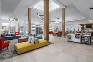Un hall d’entrée spacieux avec de hauts plafonds, un mobilier moderne et un espace salon central.