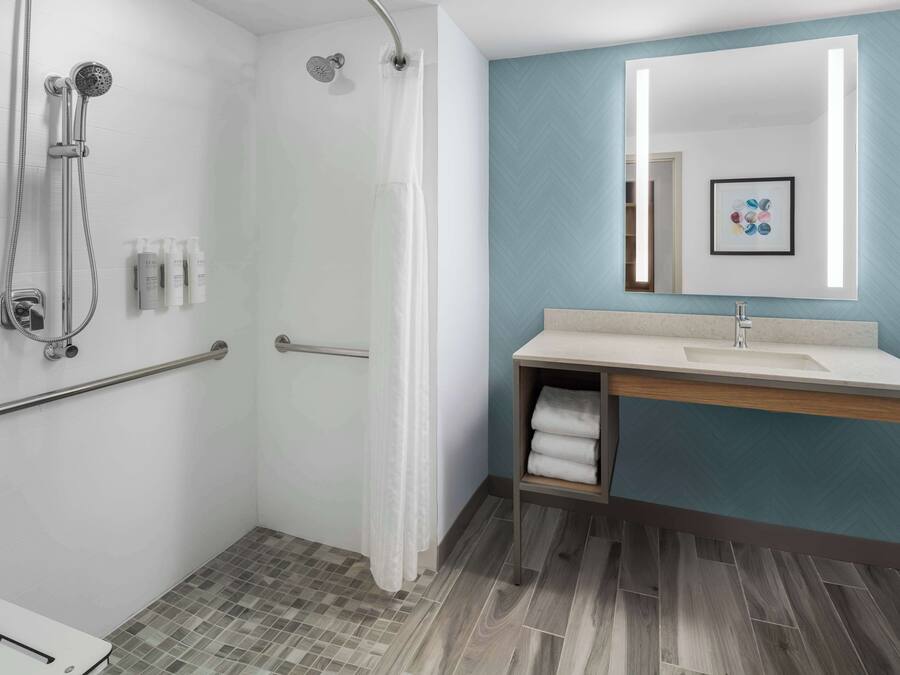 A modern bathroom with a shower, a sink, and a mirror.