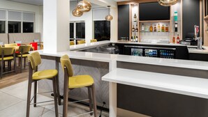 A modern bar area with a white countertop, bar stools, hanging pendant lights, and a wine display. - Hilton Garden Inn Rockaway (Rockaway)