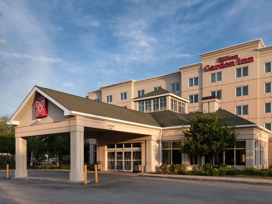 A Hilton Garden Inn with a covered entrance, multiple floors, and a clear sky.