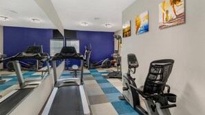 Une salle de sport équipée de tapis de course, de vélos elliptiques et d’un vélo d’appartement.