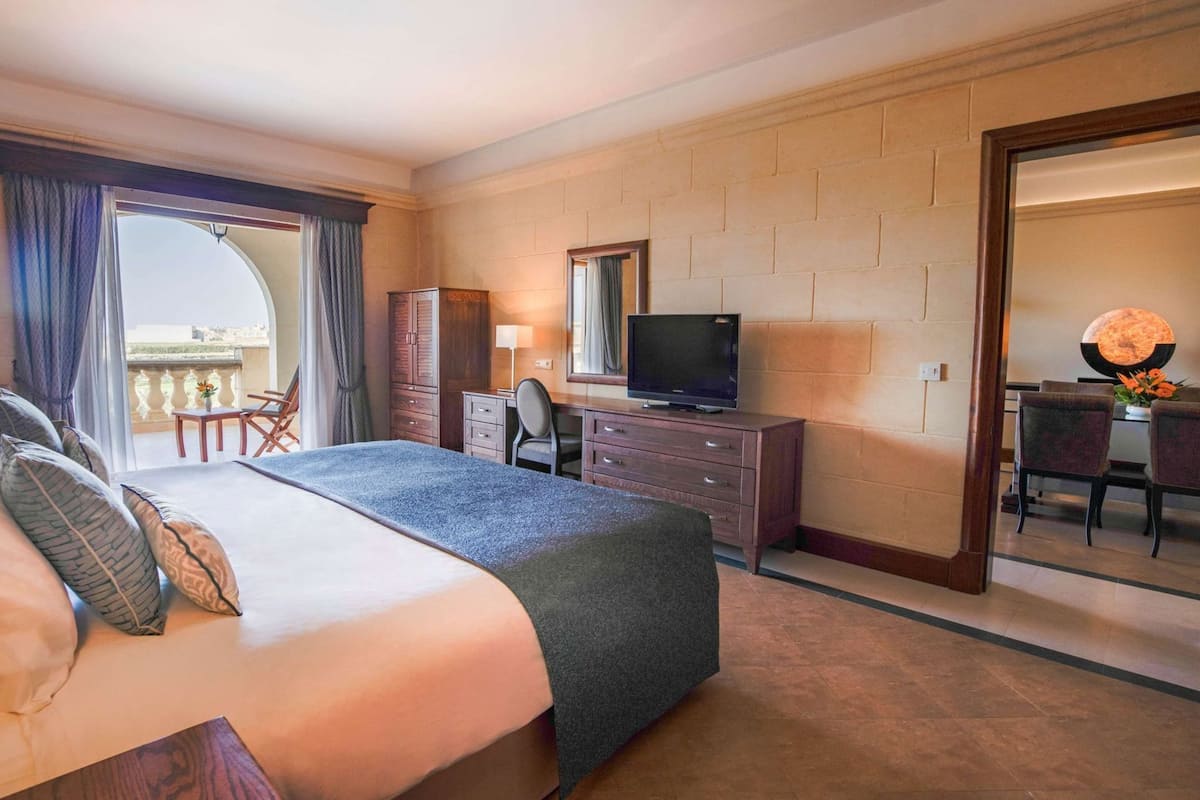 Ein Hotelzimmer mit Bett, Schreibtisch, Fernseher, Stuhl und Balkonblick.