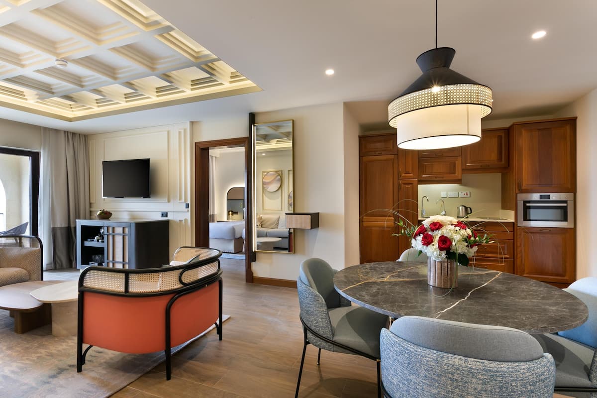 Una sala de estar moderna con comedor, cocina y televisor montado en la pared.
