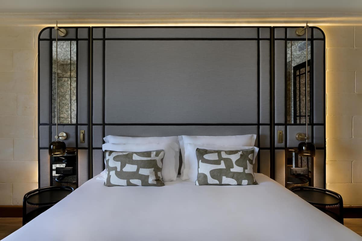 A bed with two pillows, a bedside table, and a wall-mounted light fixture.