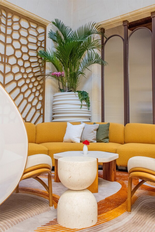 A modern living room with a mustard sofa, a round coffee table, and a decorative plant.