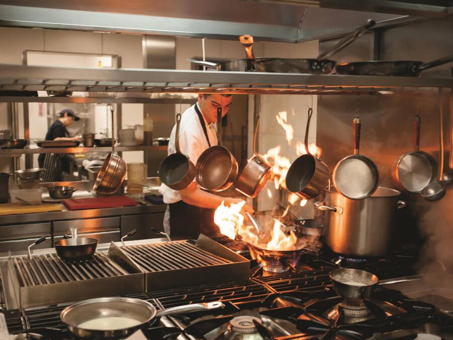 A kitchen with multiple pots on a stove, some of which are on fire.