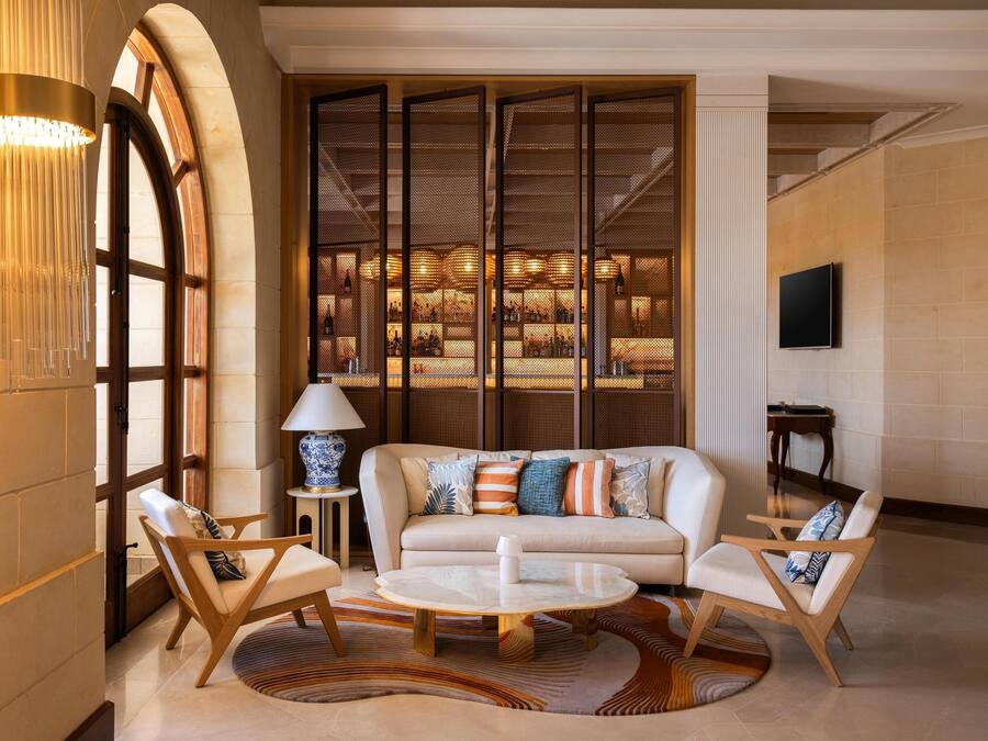 Una sala de estar moderna con un sofá, dos sillones, una mesa de centro y una lámpara decorativa.