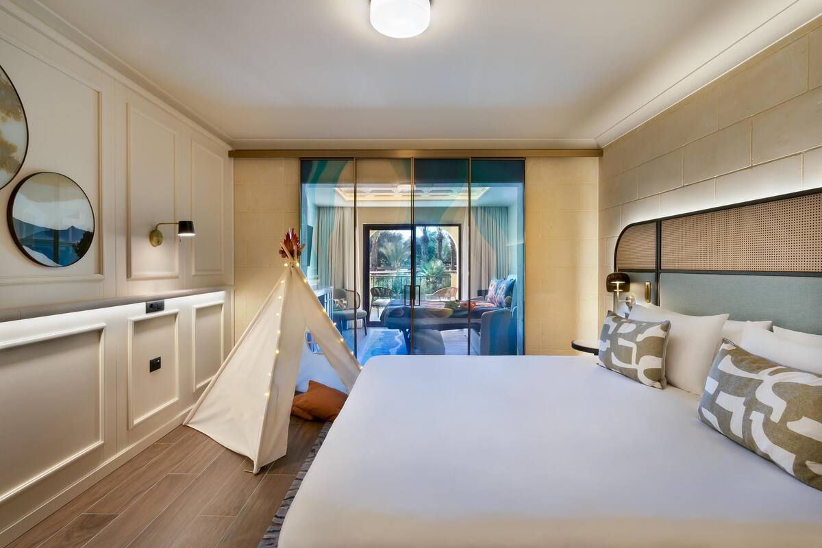 Ein Hotelzimmer mit einem großen Bett, Blick ins Freie, einem kleinen Tisch und einem Zelt.