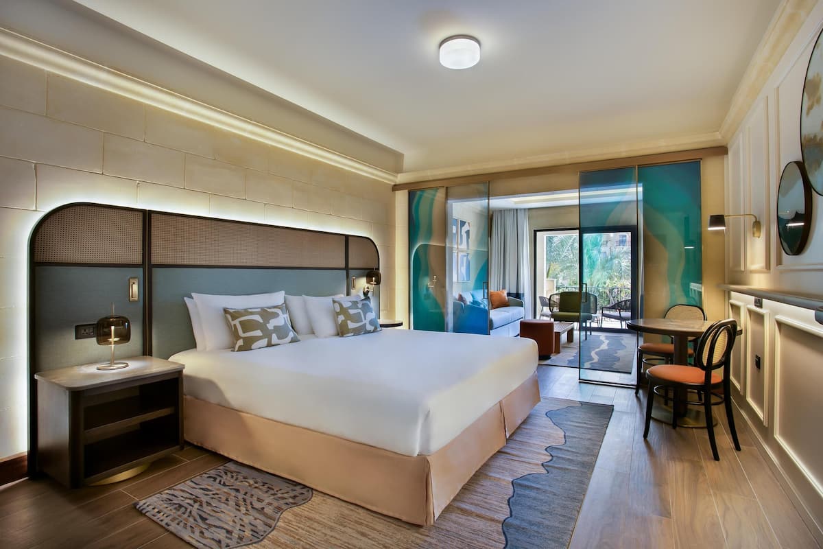 Ein modernes Hotelzimmer mit einem großen Bett, einem Schreibtisch und Blick ins Freie.