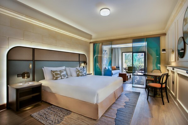 A modern hotel room with a large bed, a desk, and a view of the outdoors.