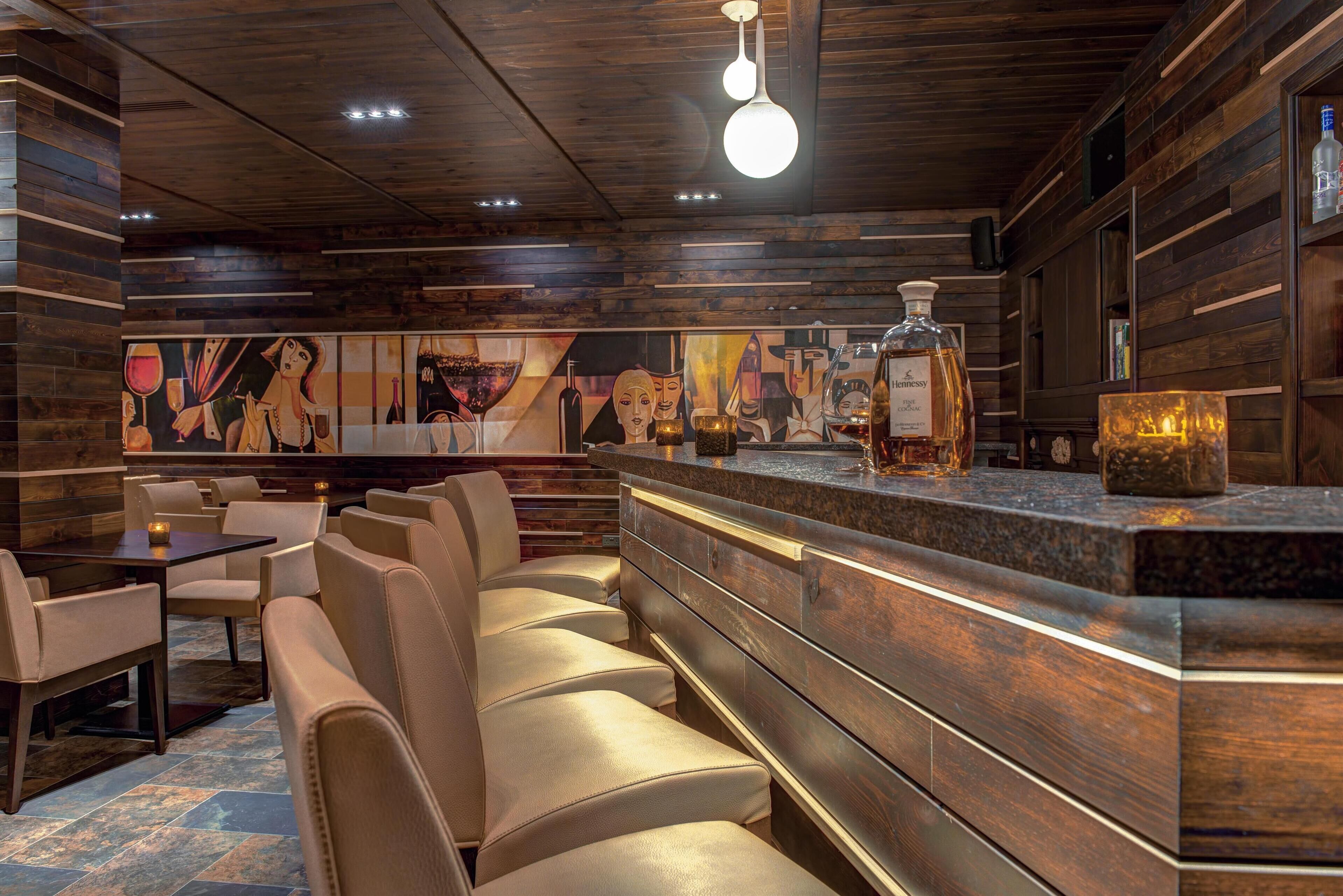 Un ristorante con pannelli in legno, un'area bar e un affresco sulla parete.