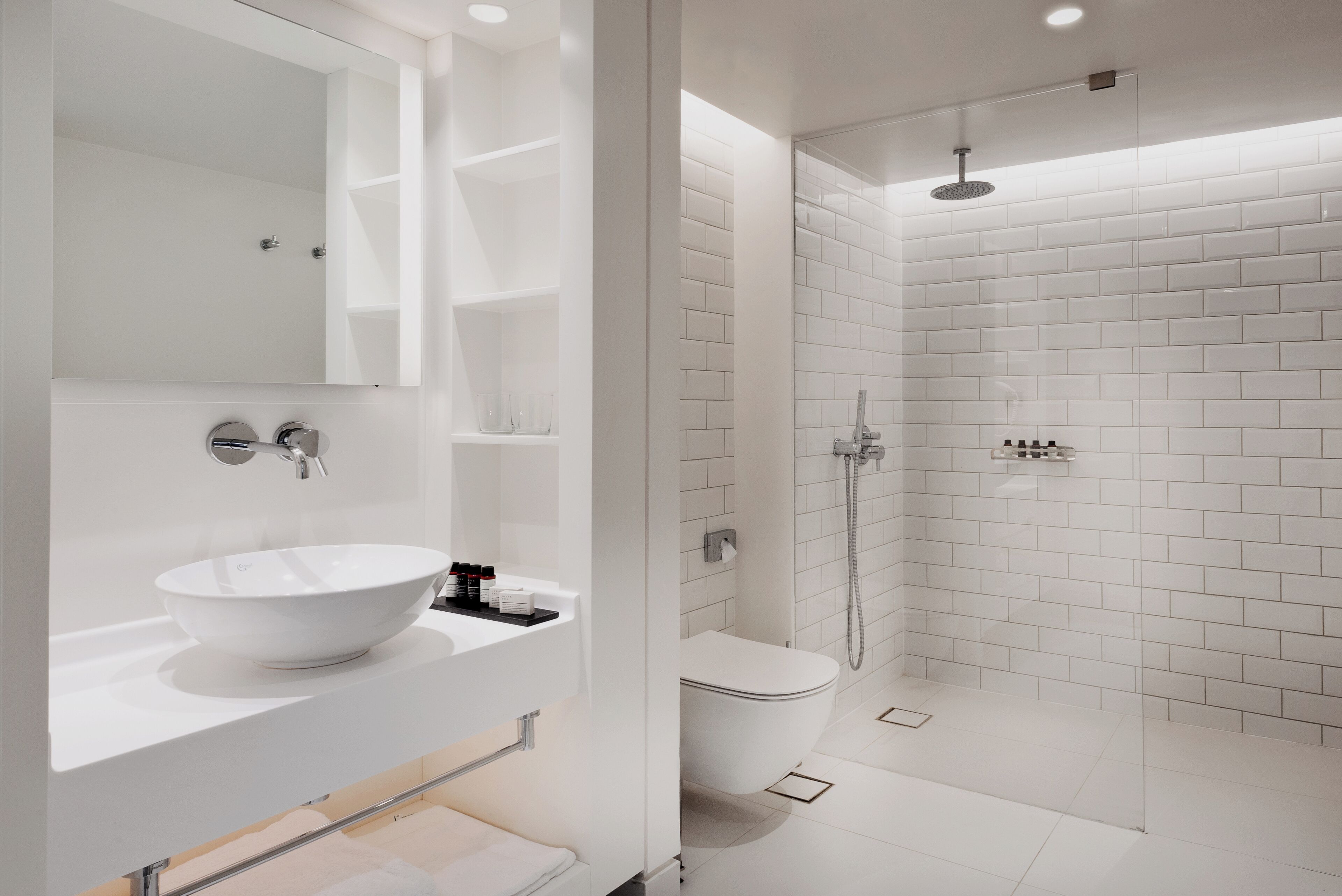 A modern bathroom with a white sink, mirror, and shower.