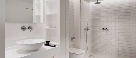 Un baño moderno con lavamanos, espejo y ducha blancos.