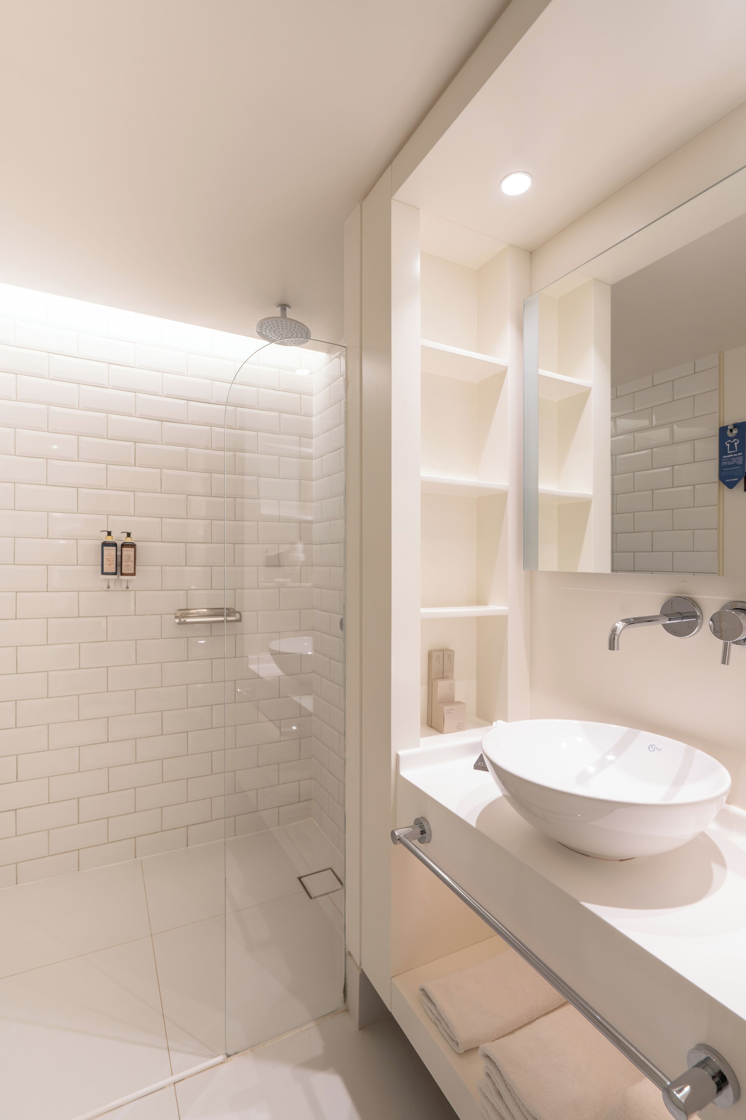 A modern bathroom with a glass-enclosed shower, a white sink, and a large mirror.