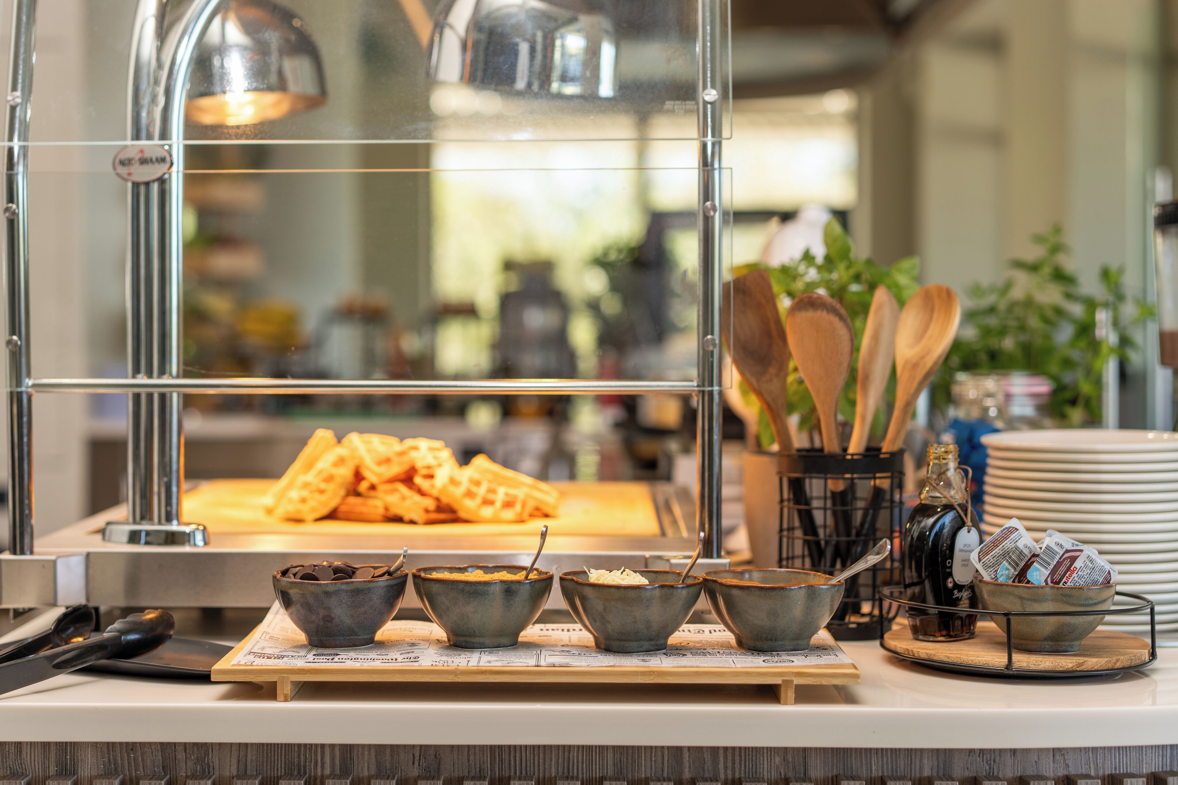 A breakfast bar with waffles, bowls of chocolate chips, and coffee.