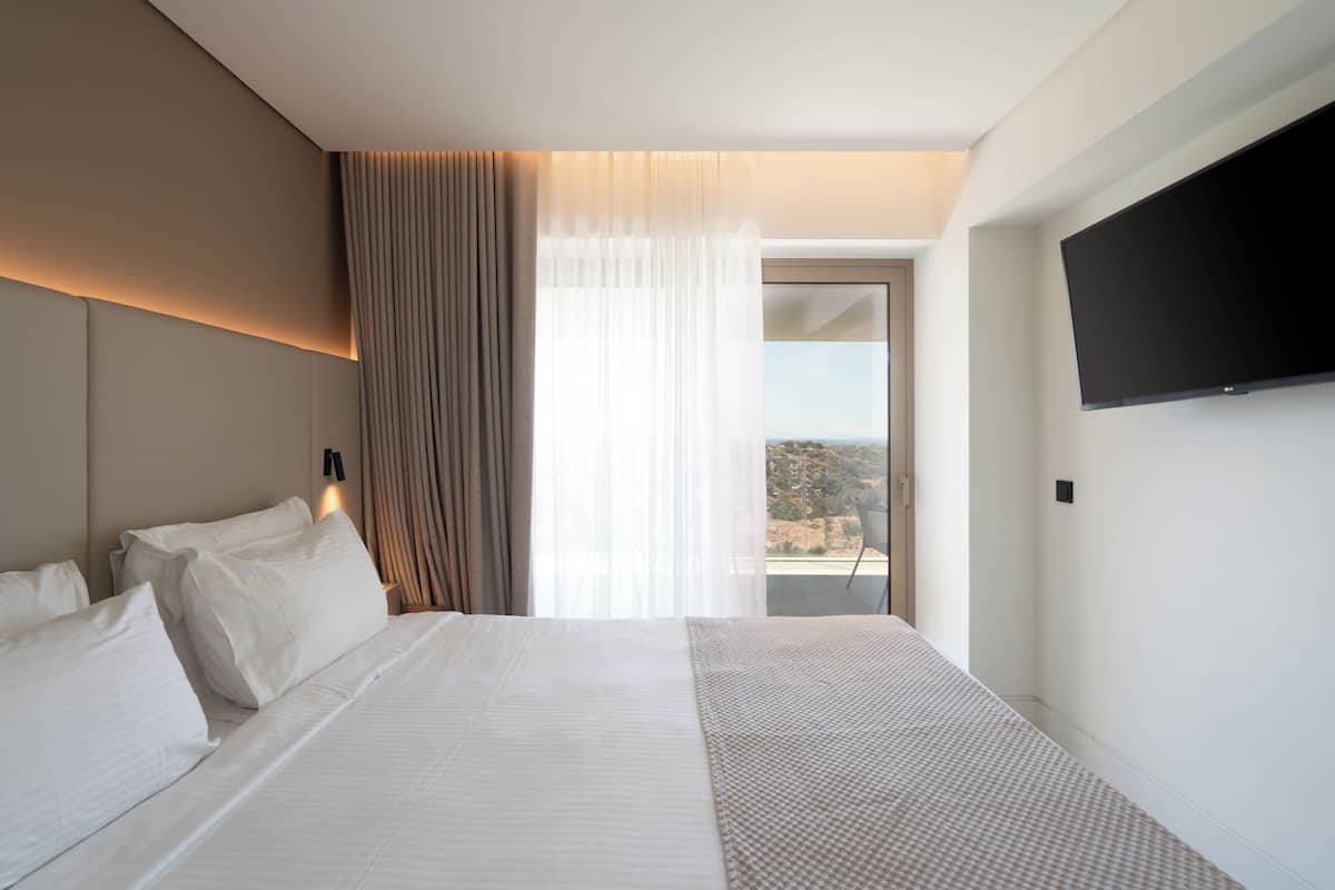 Une chambre d’hôtel dotée d’un grand lit, d’un téléviseur à écran plat et offrant une vue sur l’extérieur.