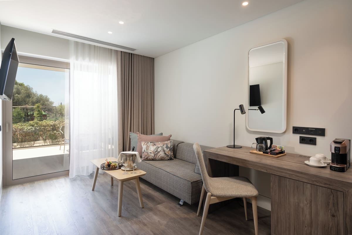 Une chambre moderne équipée d’un canapé, d’un coin café, d’une télévision et d’une grande fenêtre avec des rideaux.