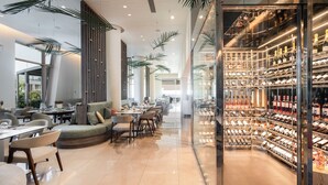 Un restaurant moderne doté d’un espace salon aux lignes courbes, d’un présentoir à vins et offrant une vue sur l’espace extérieur.