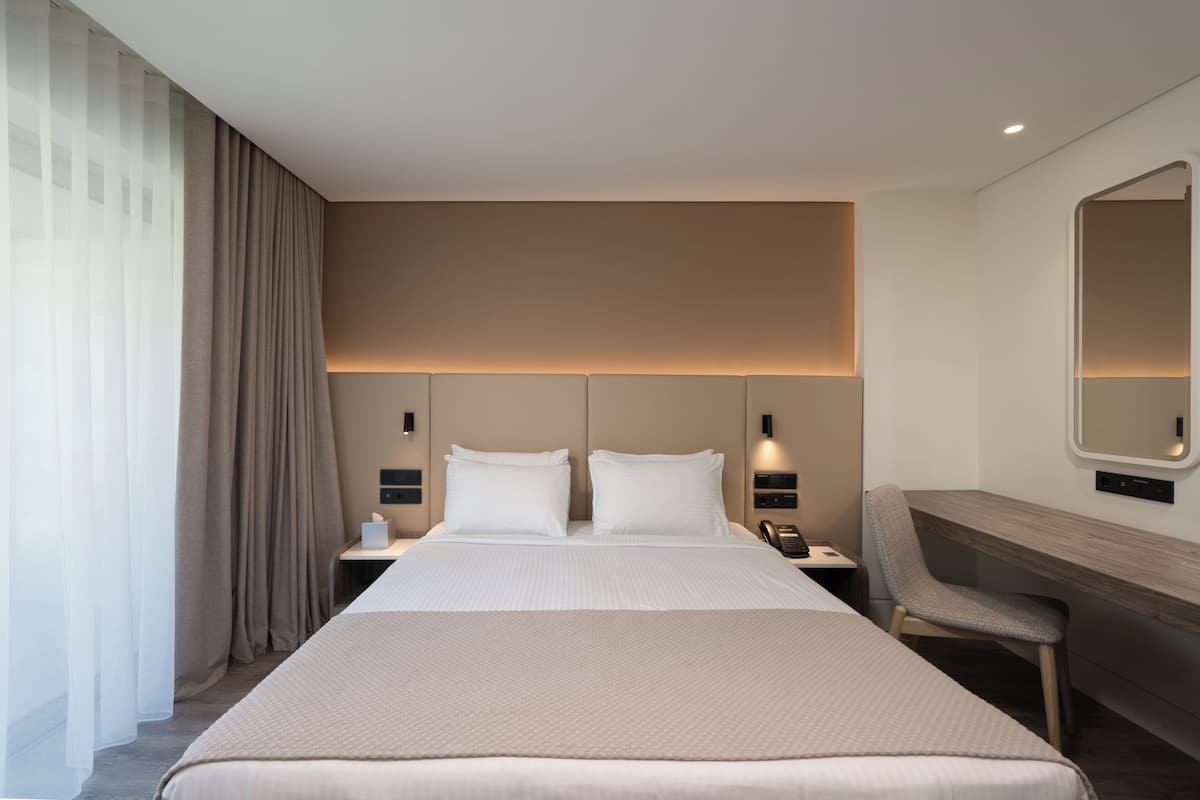 Une chambre d’hôtel avec un grand lit, des tables de chevet, un bureau et une chaise.
