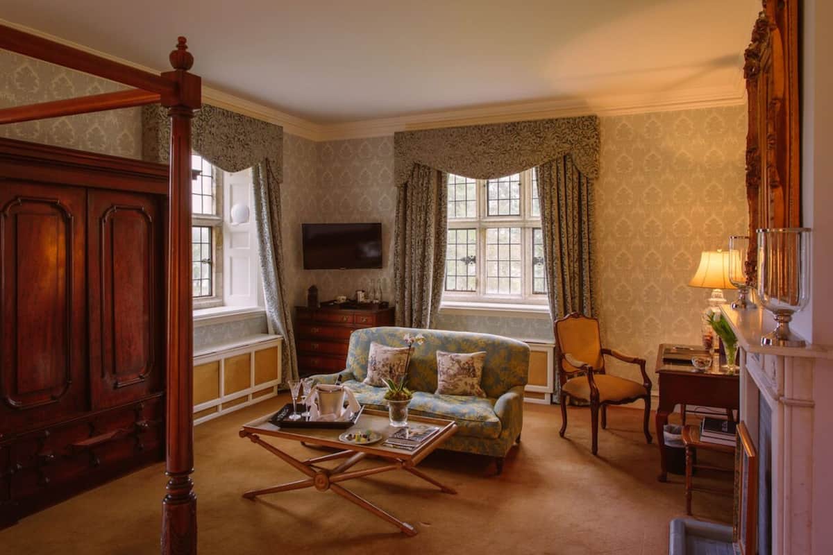 A traditional room with a four-poster bed, a sofa, a television, and a fireplace.
