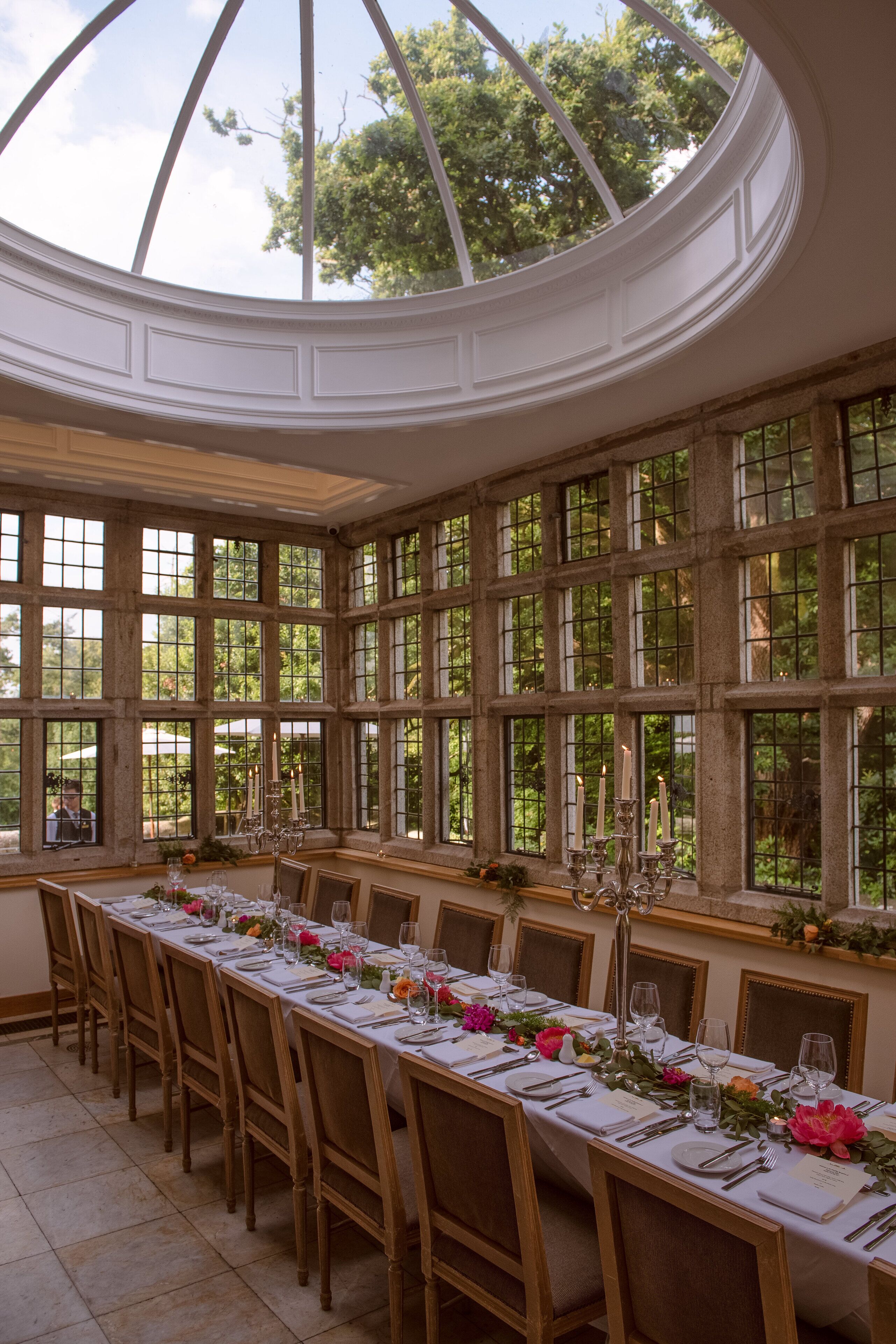 A long dining table set for a meal in a room with large windows and a dome ceiling.