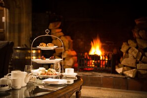 A three-tiered dessert stand with pastries and a cup of coffee on a table near a fireplace. - Waterford Castle (Waterford)