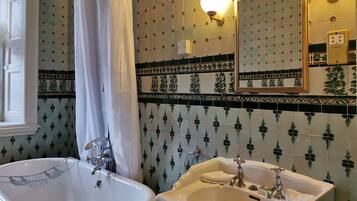 A bathroom with a bathtub, a sink, and a mirror. The walls have a patterned tile design.