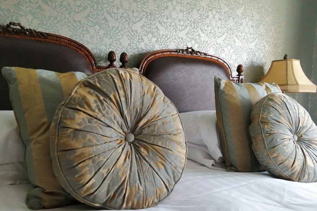 A bed with large, round, patterned pillows and a wooden headboard.