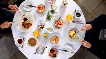A round table with various breakfast items including croissants, fruit, and beverages.