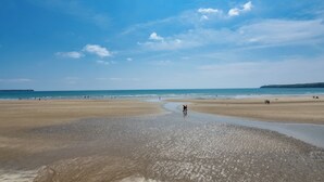 A wide beach with a clear sky and calm sea.