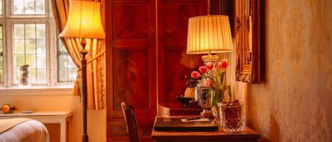 Une pièce chaleureuse avec une porte en bois, un bureau avec une lampe et un vase rempli de fleurs.