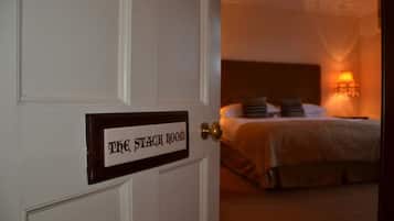 A hotel room with a bed, pillows, and a bedside lamp.