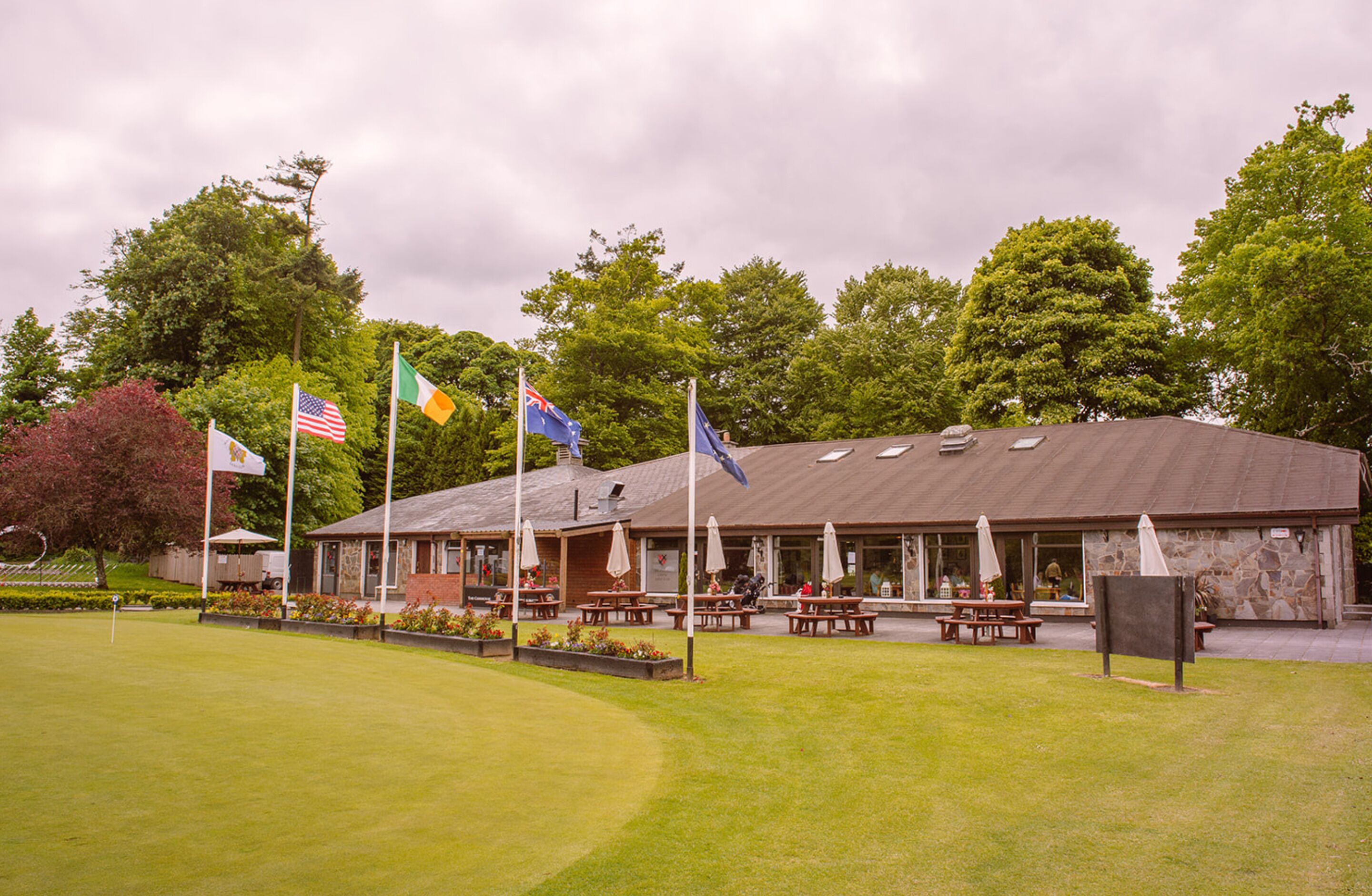 A building with multiple flags, outdoor seating, and a stone facade.